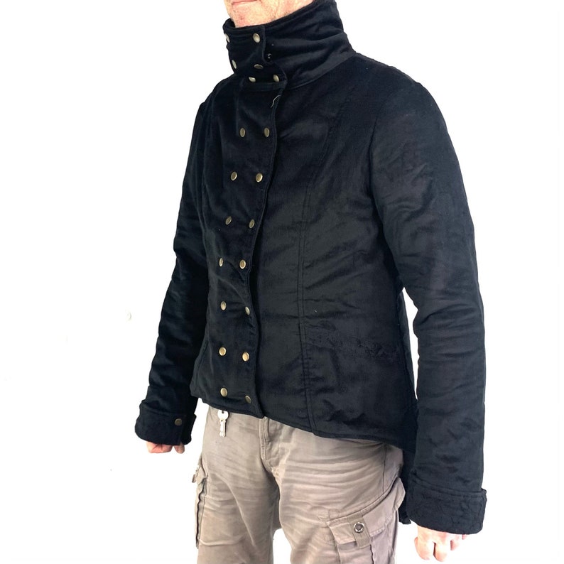 May include: A black jacket with a high collar and gold button accents. The jacket has a long, pointed hemline and a fitted silhouette.
