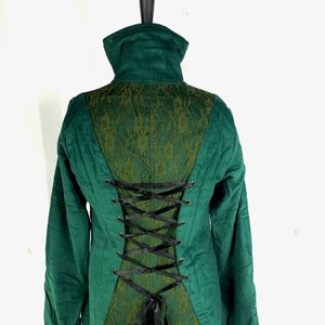 May include: A green corduroy jacket with a lace back panel and black ribbon lacing. The jacket has a high collar and long sleeves.