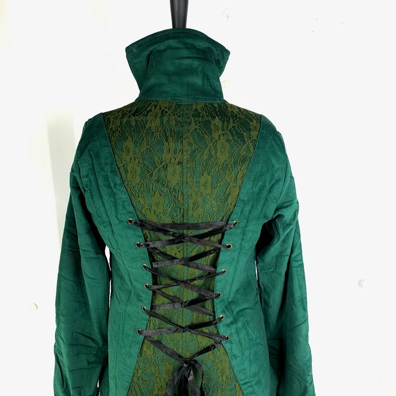 May include: A green corduroy jacket with a lace back panel and black ribbon lacing. The jacket has a high collar and long sleeves.