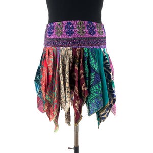 May include: A colorful, patchwork skirt with a wide, elastic waistband. The skirt features a variety of patterned fabrics in shades of red, green, purple, and teal. The skirt is displayed on a mannequin.
