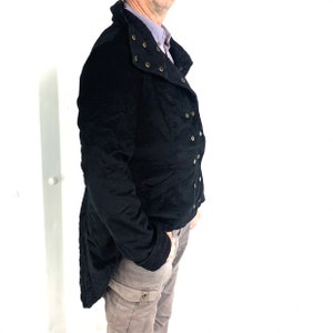 May include: A black jacket with a high collar and a long tail. The jacket has a double-breasted closure and decorative buttons.