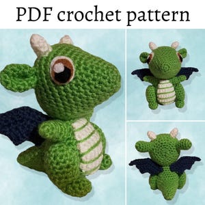 May include: A green crocheted dragon with white stripes and black wings. The dragon has large, round eyes and a small, pointed snout.
