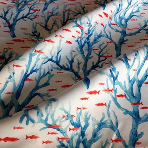 May include: White fabric with a repeating pattern of blue coral and red fish. The coral branches are detailed with a watercolor effect, and the fish are small and scattered throughout the design. The fabric has a slight sheen.