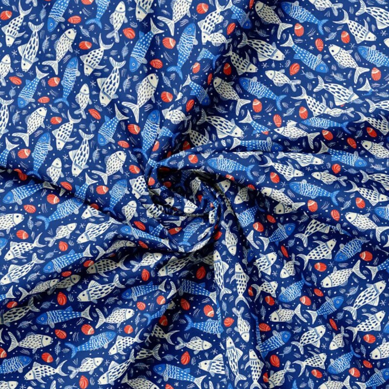 May include: A navy blue fabric with a repeating pattern of white and blue fish, red seashells, and small white stars. The fish vary in size and design, creating a nautical theme. The fabric is likely cotton or a similar material.