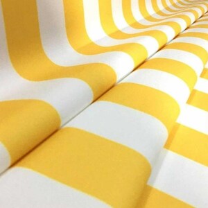 May include: Close-up of a fabric with a repeating pattern of yellow and white stripes. The stripes curve and flow across the fabric, creating a visually interesting design. The fabric appears to be soft and possibly used for clothing or home decor.