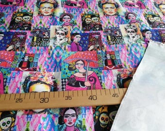 May include: A colourful fabric with a repeating pattern of Frida Kahlo portraits, skeletons, and flowers. The fabric is pink, blue, and green with a white background. A ruler is placed on top of the fabric to show the scale.