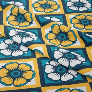 May include: A fabric with a repeating floral pattern. The design features large flowers in yellow and white, set against a teal and navy blue background. The flowers are arranged in a grid pattern with yellow square borders.