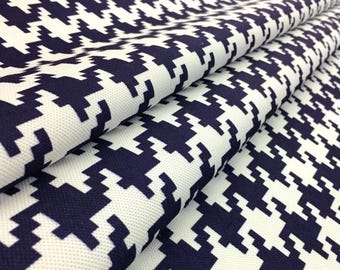 May include: Close-up of folded fabric with a navy blue and white houndstooth pattern. The fabric displays a repeating design of navy blue shapes against a white background. The material appears to be a medium-weight woven fabric.