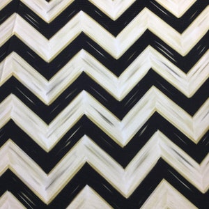 May include: A close-up of a fabric with a black and white chevron pattern. The design features bold, zigzagging lines with a subtle gold accent, creating a striking visual effect. The fabric's texture is visible, adding depth to the pattern.