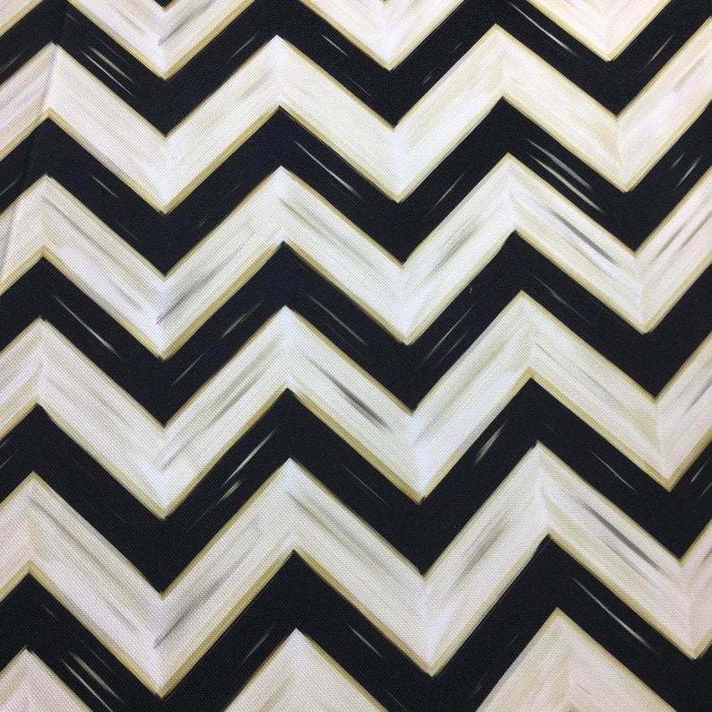 May include: A close-up of a fabric with a black and white chevron pattern. The design features bold, zigzagging lines with a subtle gold accent, creating a striking visual effect. The fabric's texture is visible, adding depth to the pattern.