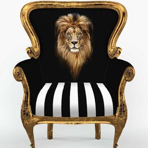 May include: An armchair with a distressed gold frame and black upholstery. The backrest features a detailed, centred portrait of a lion's head with a full mane. The seat cushion displays a bold, vertical black and white striped pattern.