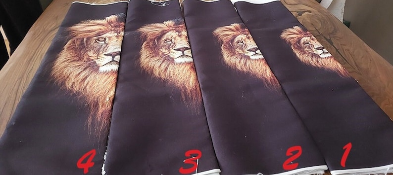 May include: Four rectangular fabric panels featuring a printed lion head design on a dark brown background. The panels are arranged side by side, each labelled with a red number from one to four, showing varying scales of the lion's face.