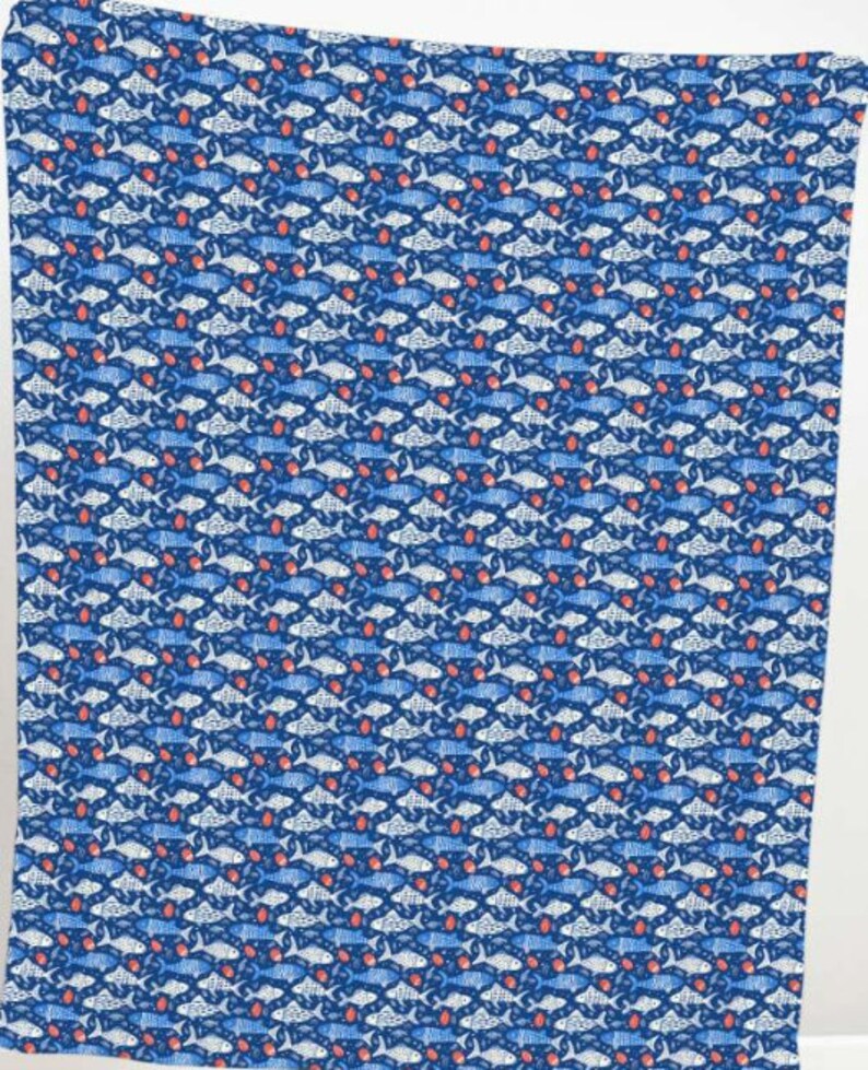 May include: A blue fabric with a repeating pattern of fish in shades of blue and white, interspersed with small red shapes. The fish are stylized and arranged in a grid-like formation, creating a visually dense and textured design.