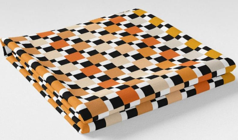 K&ouml;nnte beinhalten: Gefalteter Stoff mit einem sich wiederholenden Schachbrettmuster in Schwarz, Wei&szlig;, Orange und Beige. Der Stoff ist sauber gefaltet und zeigt das Design. Das Farbschema erzeugt eine Retro-Atmosph&auml;re.