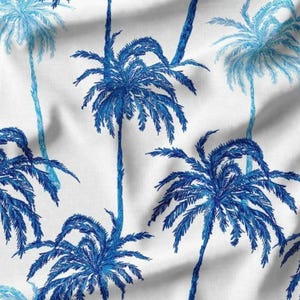 Op de afbeelding: Witte stof met een herhaald patroon van blauwe palmbomen. De palmbomen zijn in verschillende tinten blauw, waarbij sommige lichter lijken dan andere. Het ontwerp doet denken aan een tropisch of kustthema.