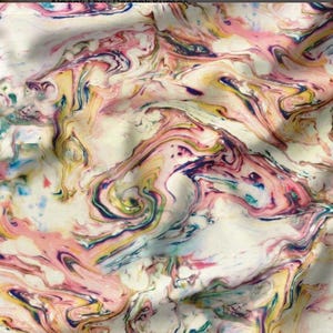 May include: Fabric with a swirling, marbled pattern in shades of pink, yellow, blue, and purple on a cream background. The design resembles flowing paint or ink, creating a dynamic and artistic look. Ideal for apparel, home decor, and craft projects.