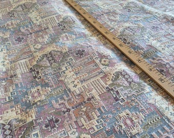 May include: A woven fabric featuring a complex geometric pattern in shades of dusty blue, mauve, cream, and tan. A wooden ruler is placed diagonally across the textile, showing measurements in centimetres up to 90 cm along its length.