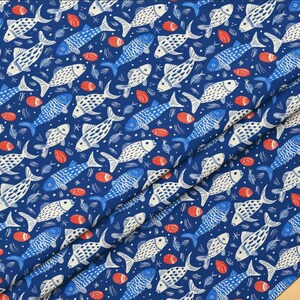 May include: A navy blue fabric with a repeating pattern of stylized fish in white and blue, along with red seashell-like shapes and small star-like elements. The fabric is folded, showing the pattern at different angles.