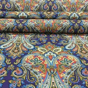 May include: Purple fabric with a paisley pattern in shades of red, orange, yellow, blue, and green.