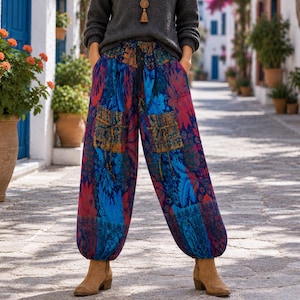 May include: A charcoal grey long-sleeved knit jumper paired with loose-fitting, ankle-length trousers featuring a vibrant, multi-coloured floral and abstract pattern in shades of blue, red, and purple, complete with a drawstring waist and tan boots.