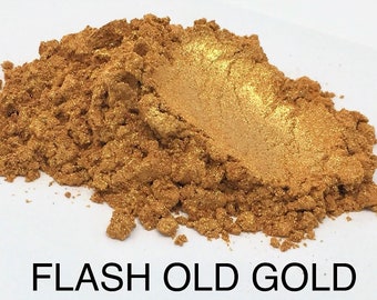 May include: A close-up of a pile of fine gold mica powder. The powder has a warm, golden hue with a slight shimmer. FLASH OLD GOLD is written in black text at the bottom of the image.