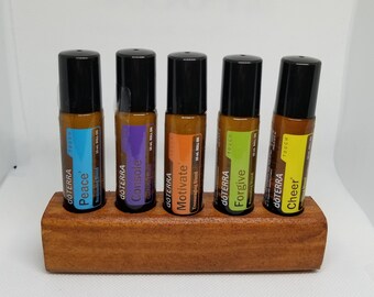 May include: Five essential oil roller bottles in a wooden holder. The bottles are labeled "Peace", "Console", "Motivate", "Forgive", and "Cheer".