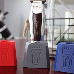 May include: Three 3D printed stands in red, gray, and blue, designed to hold an electric razor. The stands have a cutout of the razor's shape on the front. The razor is silver and has the text "CHJPro" and "Professional" on it.