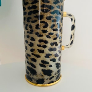 Op de afbeelding: Een thermoskan met luipaardprint, gouden rand en een transparante kunststof handvat.