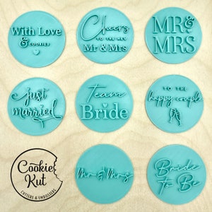 May include: Nine round cookie cutters with various wedding-themed phrases, including "With Love & Cookies", "Cheers to the New Mr & Mrs", "Mr & Mrs", "Just Married", "Team Bride", "To the Happy Couple", "Mr & Mrs", and "Bride to Be".