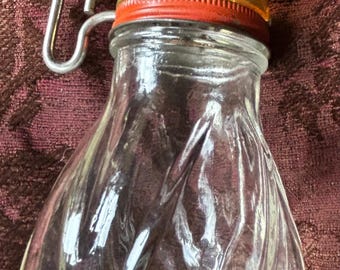 Vintage glass nut grinder with plastic measurement lid and metal crank.
