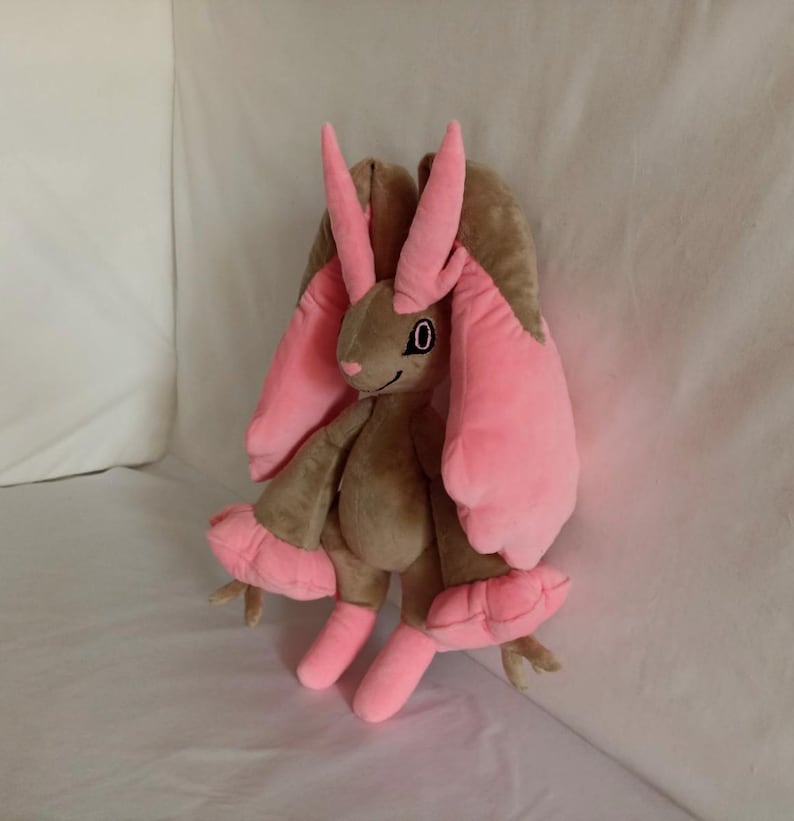 Puede incluir: Un juguete de peluche de un conejo marr&oacute;n y rosa con orejas largas y un solo ojo negro. El juguete tiene una textura suave y peluda y est&aacute; hecho de materiales de alta calidad.