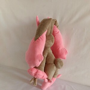 Puede incluir: Un juguete de peluche con forma de conejo de pelo marr&oacute;n y orejas rosas. El conejo est&aacute; sentado de espaldas a la c&aacute;mara.