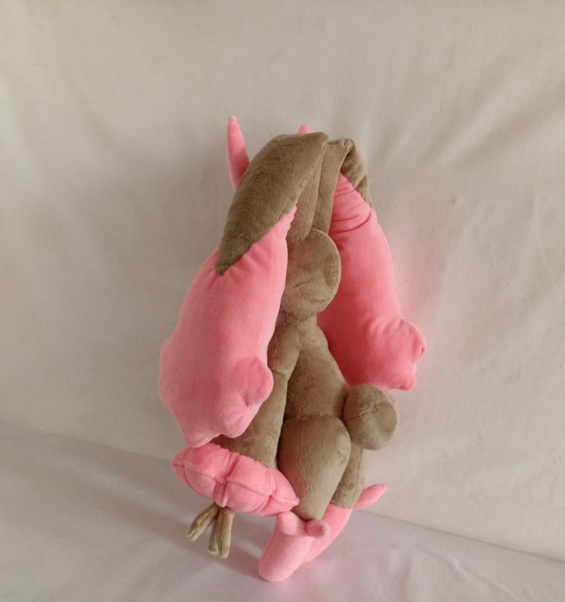Puede incluir: Un juguete de peluche con forma de conejo de pelo marr&oacute;n y orejas rosas. El conejo est&aacute; sentado de espaldas a la c&aacute;mara.
