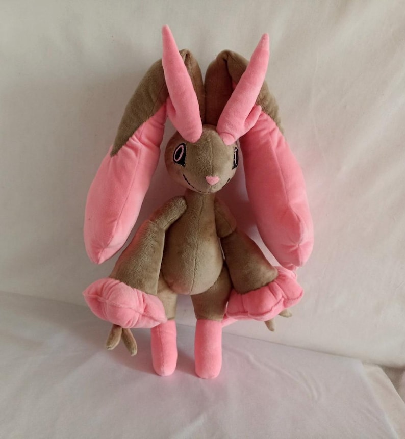 Puede incluir: Un juguete de peluche con forma de conejo con orejas largas de color rosa y un cuerpo marr&oacute;n. El juguete tiene una nariz rosa y ojos negros.