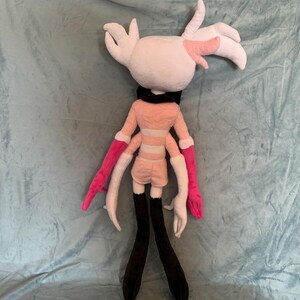 May include: A plush toy with pink and white fur, black legs, and pink and white arms. The toy has a pink and white striped shirt and a black collar.