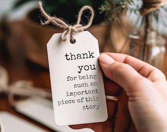 May include: A white gift tag with a brown twine bow. The tag says "thank you for being such an important piece of this story".
