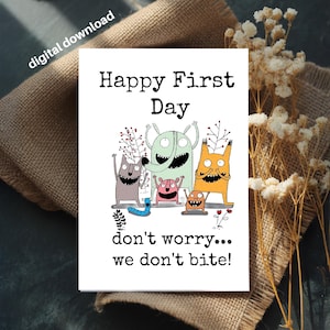 Puede incluir: Una tarjeta blanca con el texto "Happy First Day" y la frase "don't worry... we don't bite!" rodeada de monstruos de dibujos animados de varios colores. La tarjeta está sobre una superficie de arpillera con flores secas.