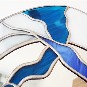 Op de afbeelding: Close-up van een glas-in-loodspiegel met een blauw en wit ontwerp. De spiegel is ingelijst met zilverkleurig metaal.