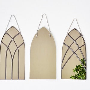 Puede incluir: Tres espejos arqueados con un diseño de vitral. Los espejos están colgados de cadenas y tienen un acabado plateado.