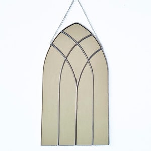May include: A silver arched mirror with a stained glass design. The mirror is hanging from a silver chain.