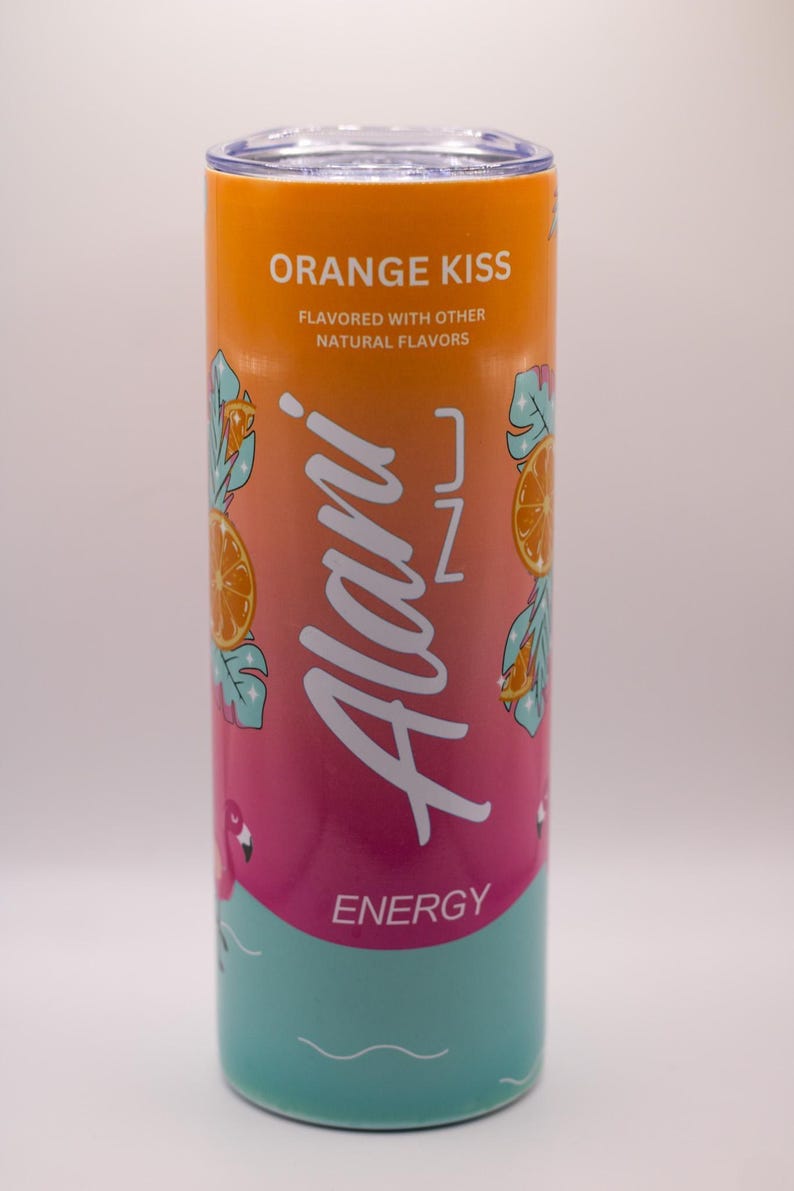May include: A cylindrical, insulated tumbler with a gradient design of orange, pink, and teal. The tumbler features the text "ORANGE KISS" and "Alani Nu ENERGY" with orange slice and flamingo graphics. It is flavored with other natural flavors.