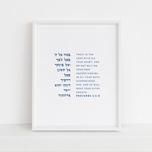 Könnte beinhalten: Ein weißer gerahmter Druck mit blauem hebräischem Text und englischer Übersetzung von Sprichwörter 3:5-6. Der Text lautet: "Vertraue auf den Herrn von ganzem Herzen, und verlass dich nicht auf deinen eigenen Verstand. Erkenne ihn auf all deinen Wegen, und er wird deine Pfade ebnen. Sprichwörter 3:5-6"