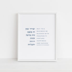 May include: A framed print with text in Hebrew and English. The English text reads "MAY THIS BUSINESS BE BLESSED WITH PROSPERITY, FORTUNE, HAPPINESS AND SUCCESS." The frame is white, and the background is white.