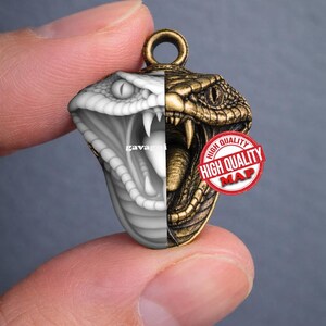 May include: A pendant featuring a detailed cobra design, split vertically with a grayscale and bronze finish. The pendant has an eyelet for a chain and a "HIGH QUALITY MAP" stamp.