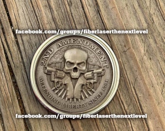 May include: A silver-colored coin with the text "2ND AMENDMENT" and "DEFENDING LIBERTY SINCE 1791". The coin features a skull and two revolvers. The text "facebook.com/groups/fiberlaserthenextlevel" is at the top and bottom.