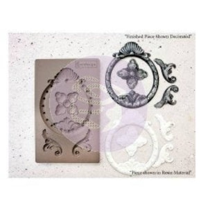 May include: A silicone mold for creating decorative elements. The mold features a large oval frame with floral details and two smaller scroll designs. "Finished Piece Shown Decorated" and "Piece Shown in Resin Material" are printed on the white background.