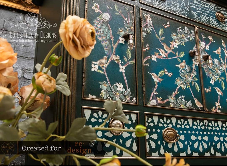 Peut inclure: Un cabinet bleu sarcelle avec des garnitures dor&eacute;es orn&eacute;es et des motifs floraux et d'oiseaux d&eacute;coratifs. Le cabinet a plusieurs tiroirs avec des motifs d&eacute;coup&eacute;s complexes et des boutons en m&eacute;tal. Le texte "LOTUS THEORY DESIGNS" et "www.lotustheorydesigns.com" est visible sur le cabinet.