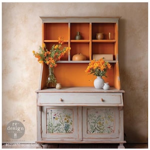 May include: A vintage hutch with a gray painted finish and a bright orange interior. The hutch has a top shelf with a glass door and a lower cabinet with two doors. The doors are decorated with a floral pattern. The hutch is decorated with flowers and vases.