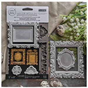 May include: A package of gray silicone molds for crafting, featuring ornate picture frames and decorative elements. The package is labeled "DECOR MOULDS MINIATURE GRACE" and measures 5" x 8". The molds are food safe.