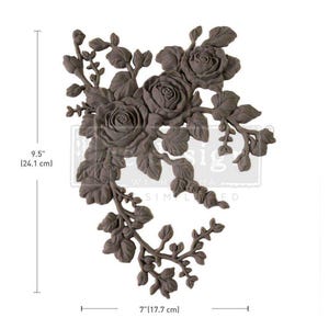May include: A decorative floral design with a cluster of roses and leaves. The design is made of a dark brown material and measures 9.5 inches tall and 7 inches wide.